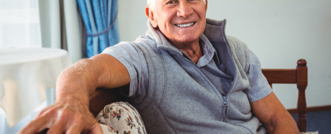 Smiling senior gentleman sitting on couch