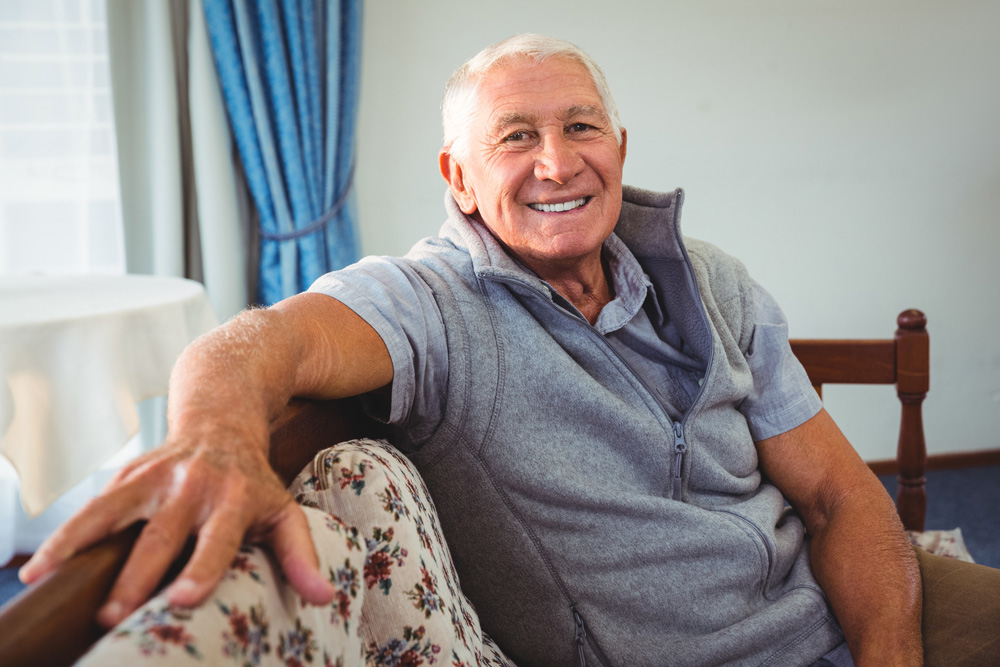 Smiling senior gentleman sitting on couch