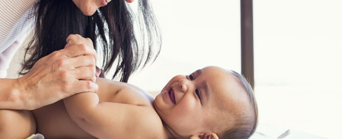 Smiling mom with smiling baby on blanket