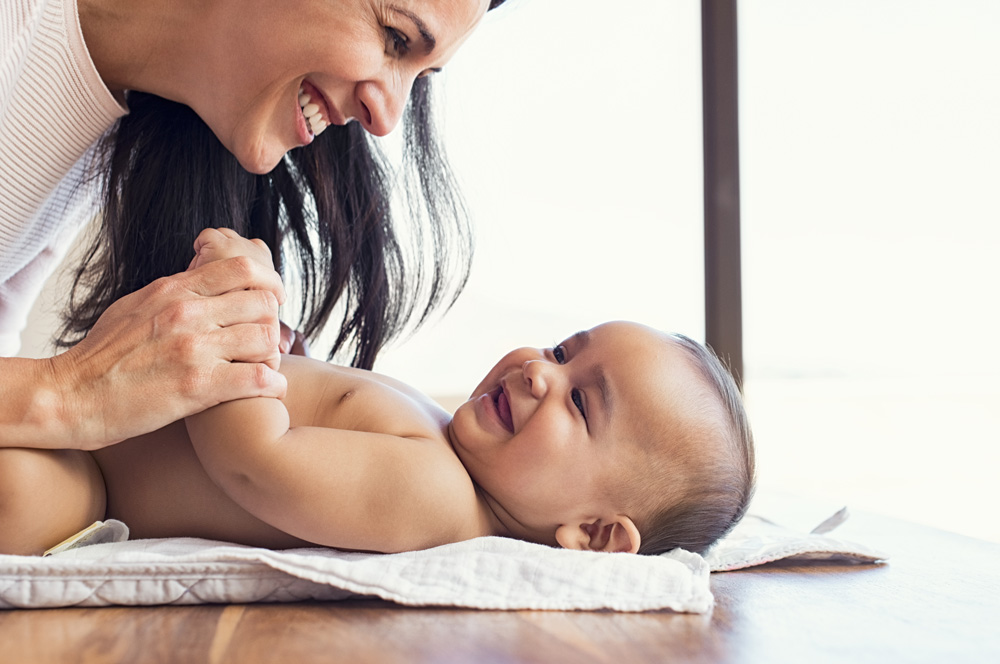 Smiling mom with smiling baby on blanket